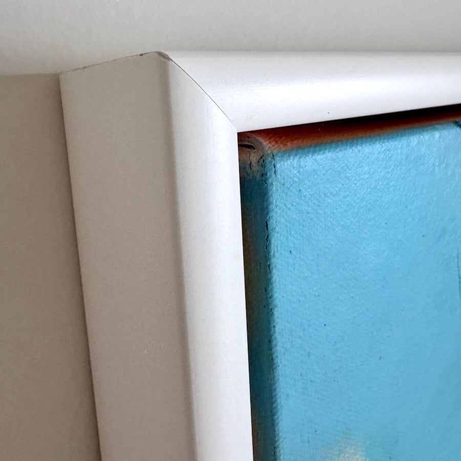 Close-up of a white floating frame corner with a blue wall art