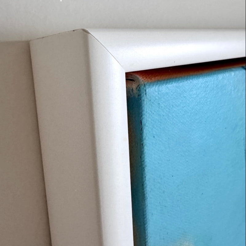 Close-up of a white floating frame corner with a blue wall art