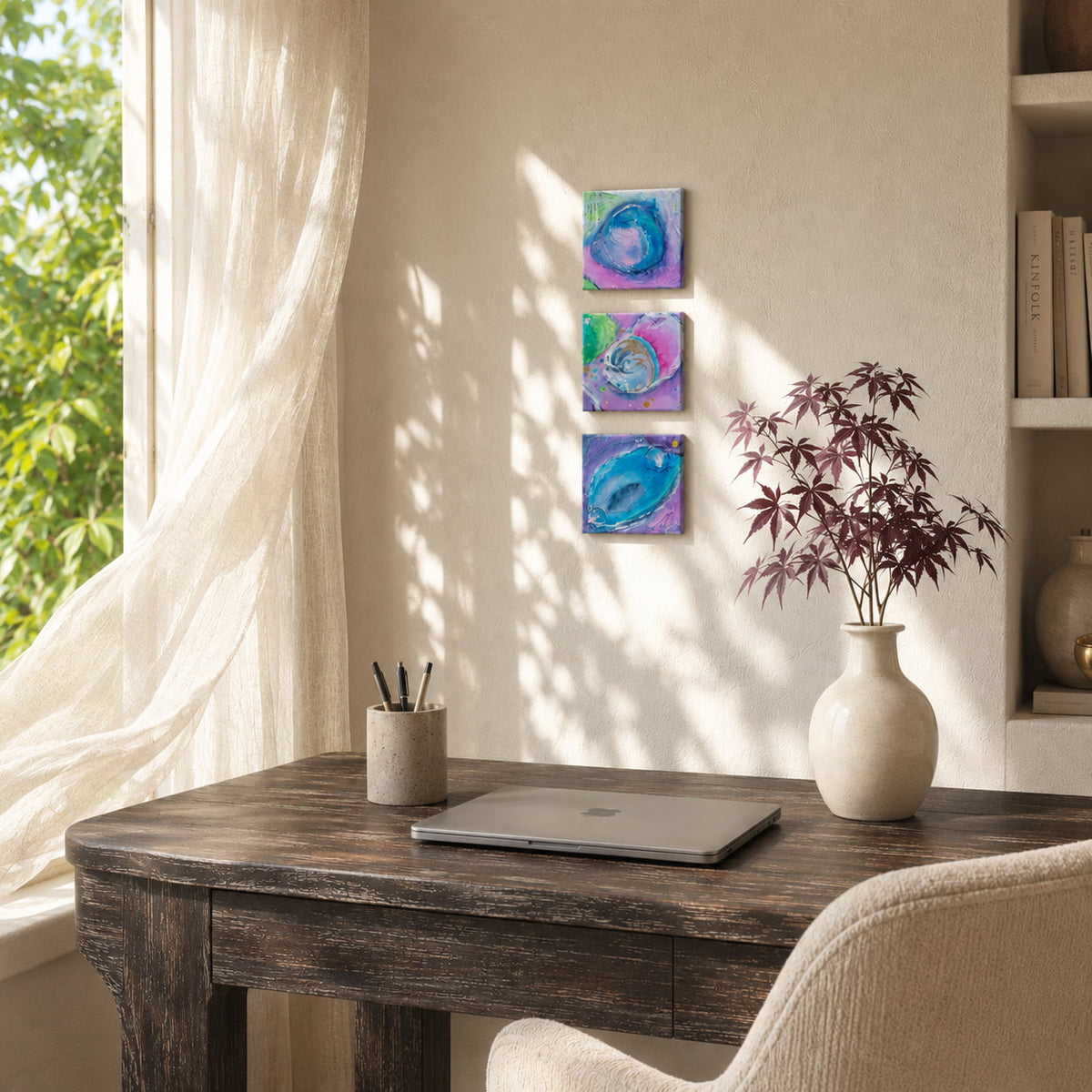 Three original abstract paintings displayed above a dark wood home office desk