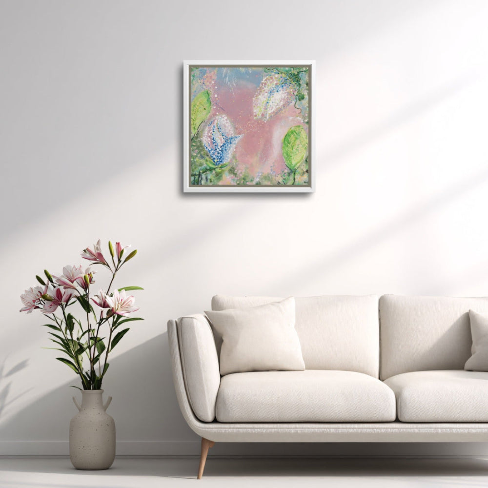 Framed abstract artwork on a wall above a white sofa with a vase of flowers.
