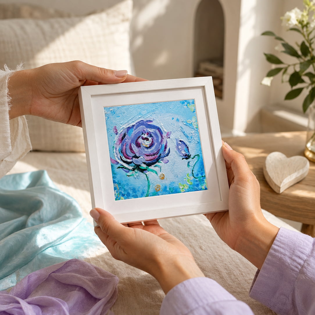 Woman's hands holding the framed Mini Miracle art print above a bed