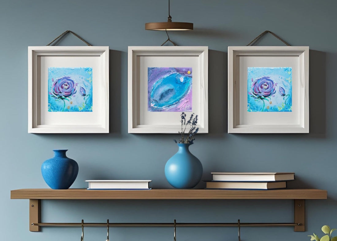 Three framed blue and purple art prints displayed above a wooden shelf