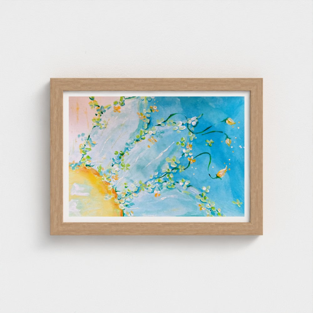 A framed abstract floral wall art print featuring blue, white, yellow, and green brushstrokes, presented in a light natural wood frame against a clean white wall.