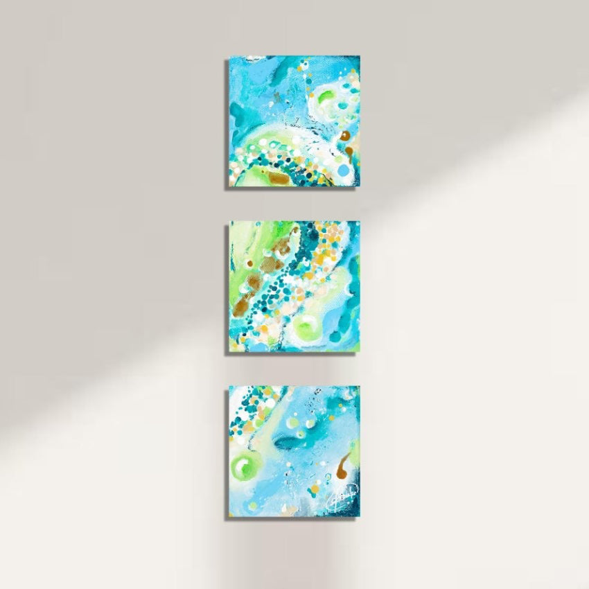 Three abstract paintings on a wall above a beige sofa
